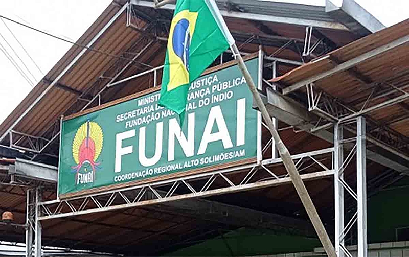 Banner da FUNAI pendurado em um edifício com a bandeira brasileira ao lado.